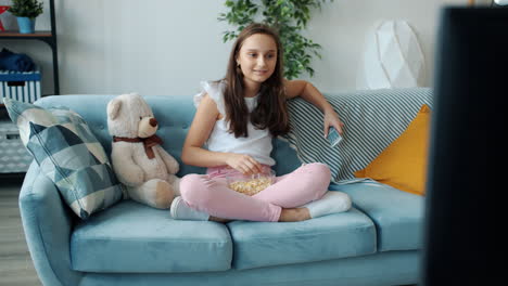 teenage girl watching tv and eating popcorn
