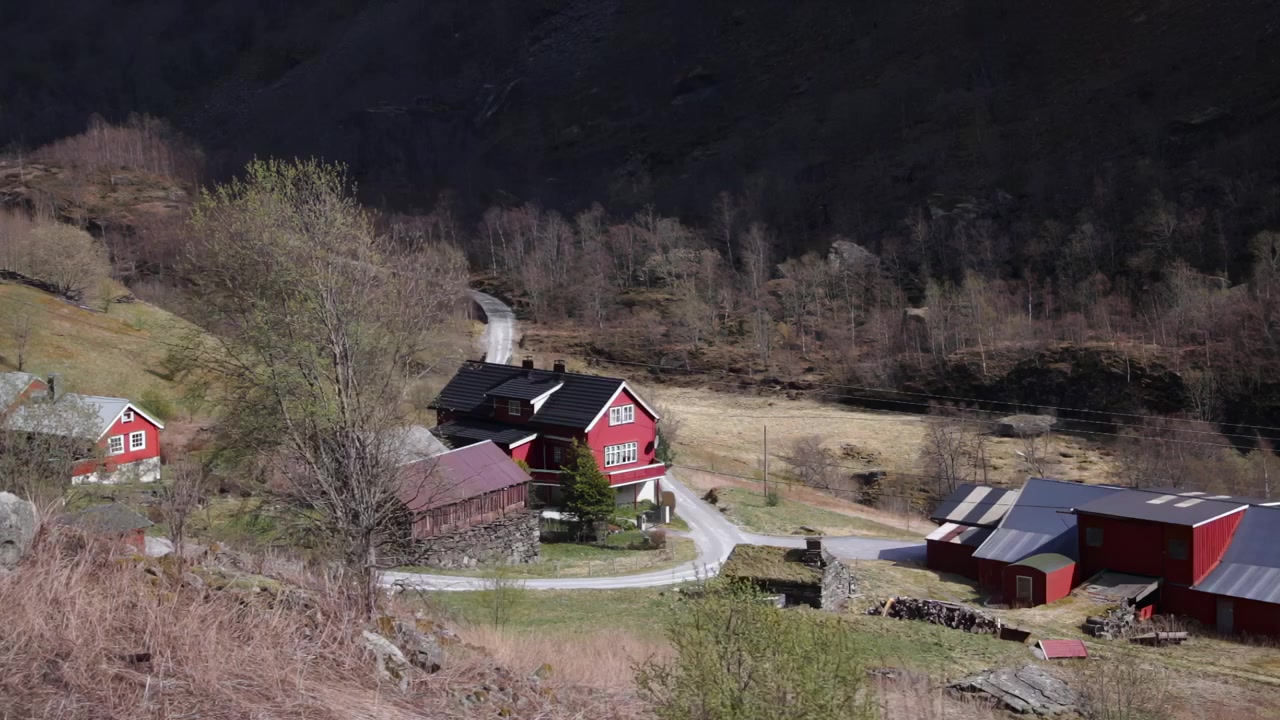 Punaisia maalaistaloja ja mutkitteleva tie maaseudun Aurlandsfjordin laaksossa, varhaiskevään maisema, Norja, Eurooppa