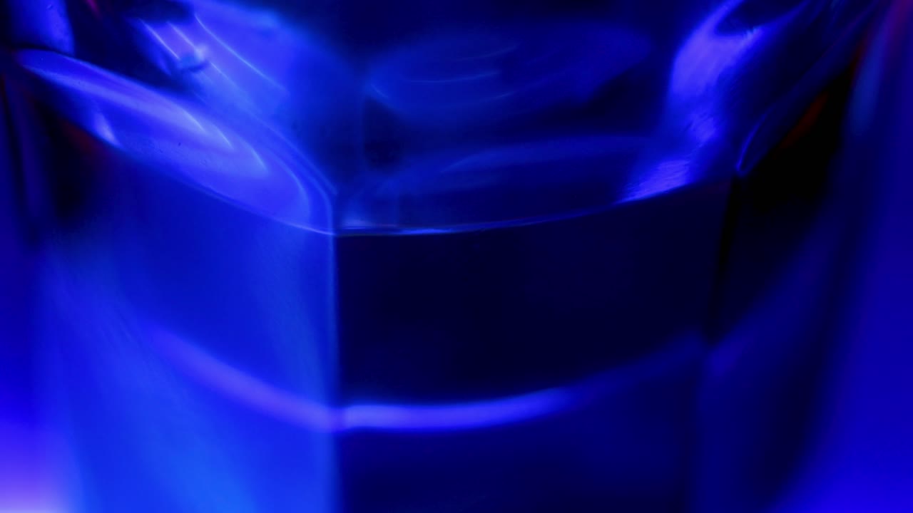 Parte inferiore di un bicchiere con la luce blu futuristica di un pub, scatto macro ravvicinato