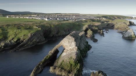 Una-Vista-Aérea-De-Bow-Fiddle-Rock-En-Portknockie-En-Una-Tranquila-Mañana-De-Verano