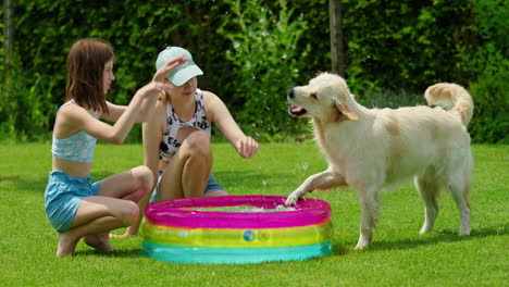 dos chicas y su perro jugando con una piscina inflable