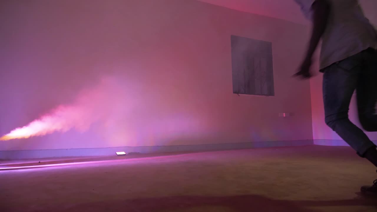 jóvenes africanos corriendo y saltando sobre una pared y haciendo una voltereta hacia atrás con luces estroboscópicas de colores y humo