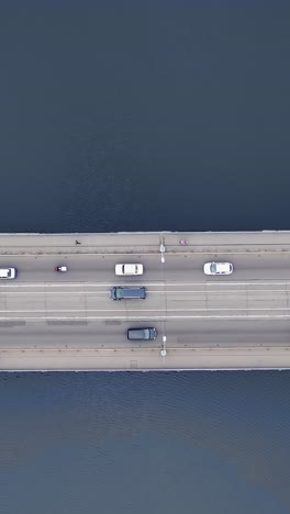pedestrians and cars move across the bridge in the city. view from the top. aerial view. vertical video