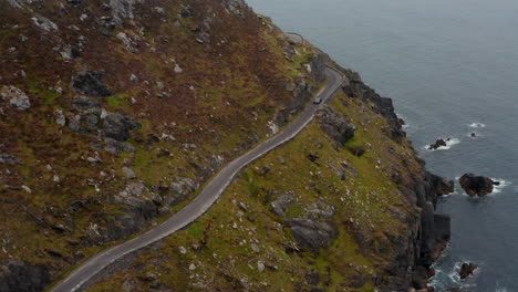 Vista-De-ángulo-Alto-De-La-Curva-De-Paso-Del-Automóvil-Y-La-Carretera-Estrecha-Por-Encima-De-La-Costa-Del-Mar.-Impresionante-Ruta-Panorámica.-Irlanda