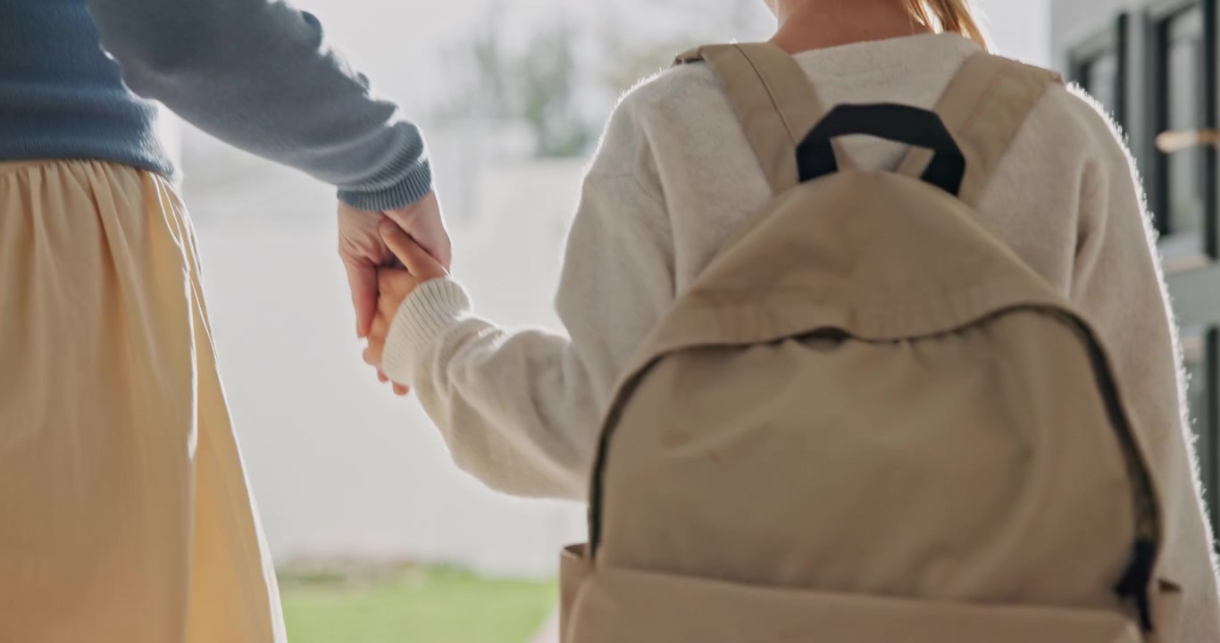 Madre che tiene per mano un bambino con lo zaino prima della scuola