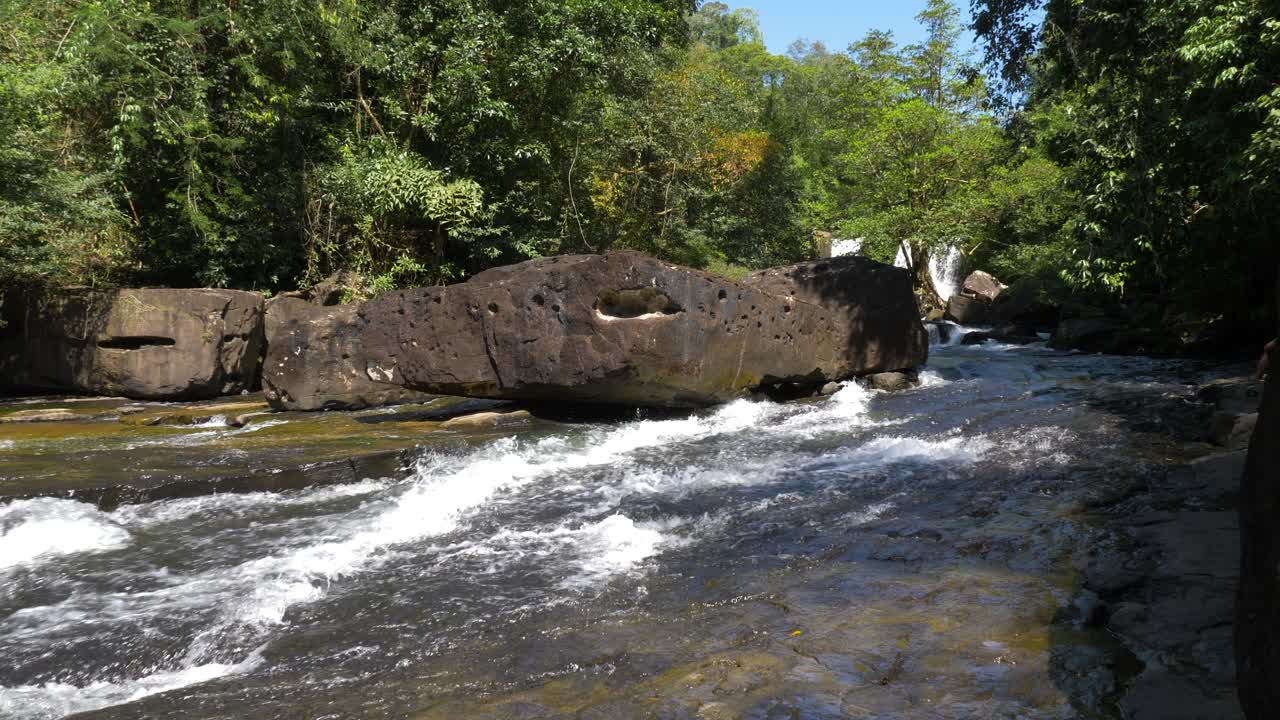 Ampia inquadratura dell'acqua che si riversa nel fiume da una piccola cascata.