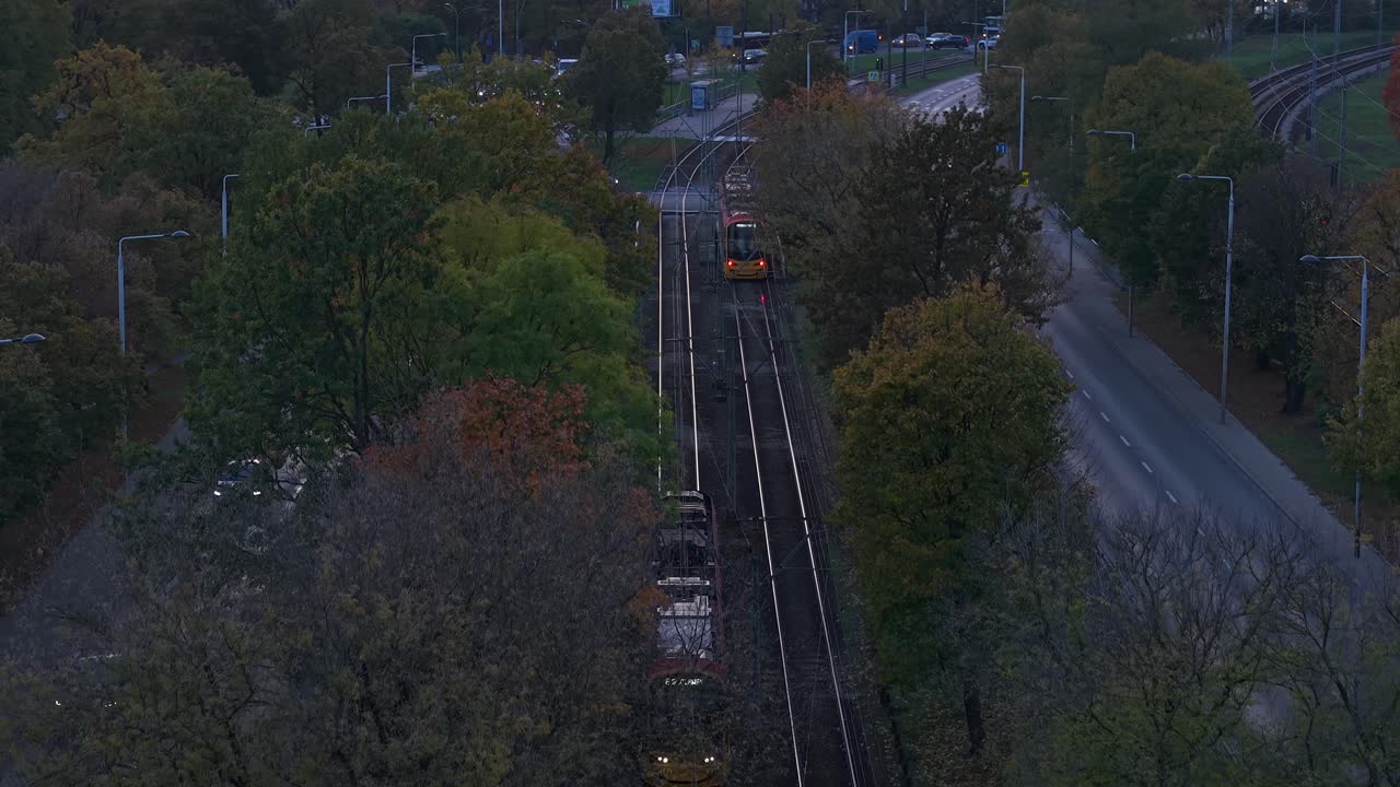 Warsaw, Poland, Drone Shot of Two Trams Passing in Opposite Direction and Street Traffic in Suburbs in Autumn Season