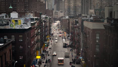 looking down a busy city street as pedestrians and cars commute