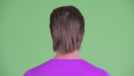zoom in shot of young man back view against green background