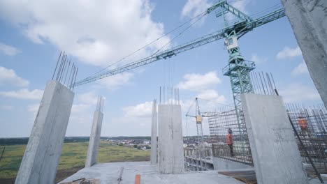 las grúas de torre trabajan en la construcción de edificios residenciales de ladrillo contra el fondo de un cielo azul.