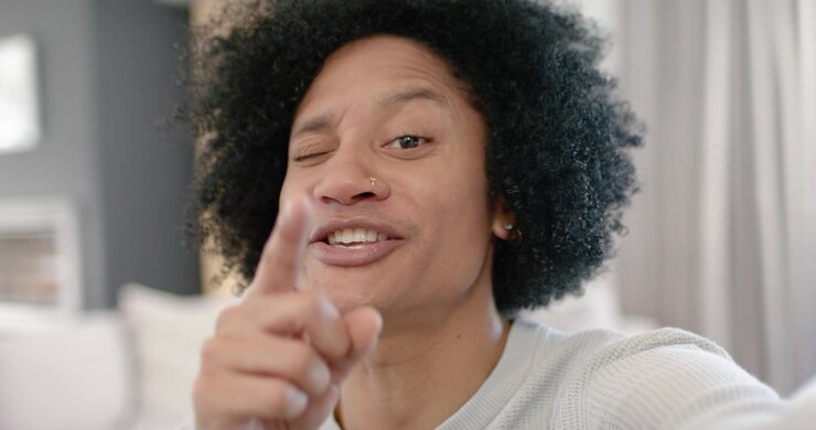African American man raising fist, speaking, stressing, smiling and winking at home with nose ring