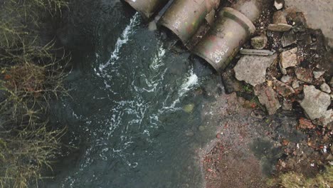 streams of water flow through concrete sewers. polluted body of water in the park. shooting from the drone with the camera down.