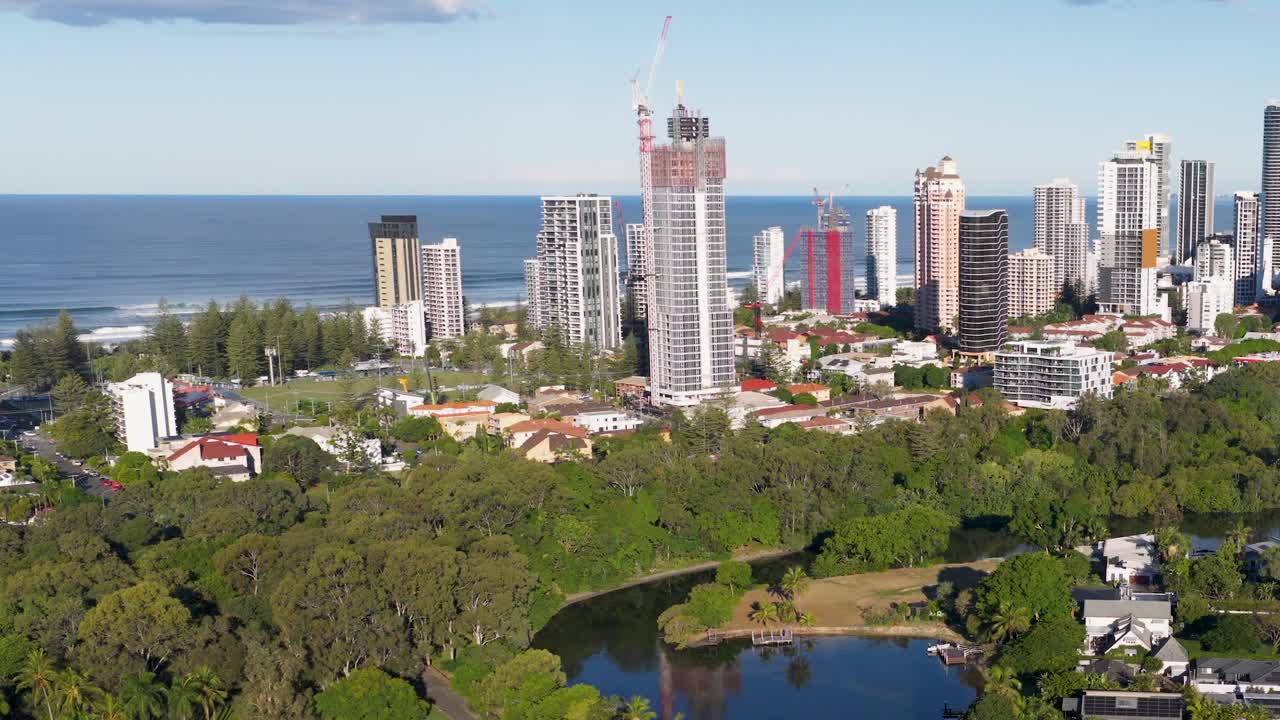 Aerial footage captures Gold Coast's skyline and lush greenery under bright daylight, showcasing urban and natural harmony