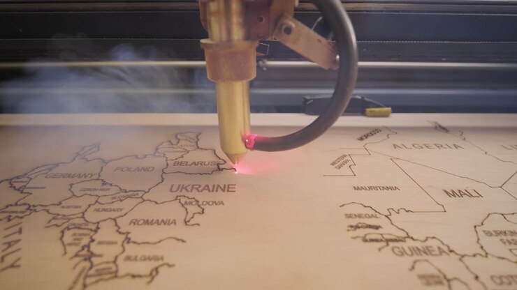 CNC-laserskæremaskine skærer verdenskort på træplanke og krydsfiner.
