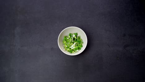 hand grabbing bowl of chopped spring onions