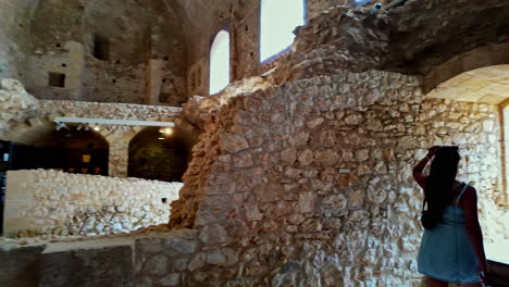 following shot of a female tourist walking out of medieval chlemoutsi castle in kastro village, peloponnese, kyllini-andravida, greece on a sunny day