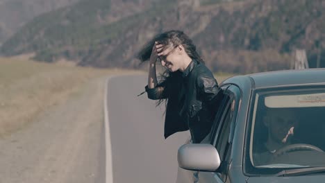 fabulosa mujer delgada se inclina hacia fuera de la ventana del coche y baila