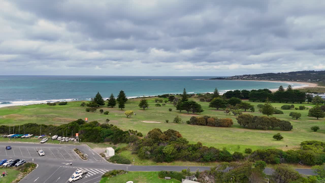 Drone footage captures Lorne's coastline, parkland, and ocean under cloudy skies. The camera pans smoothly, showcasing natural beauty and tranquility