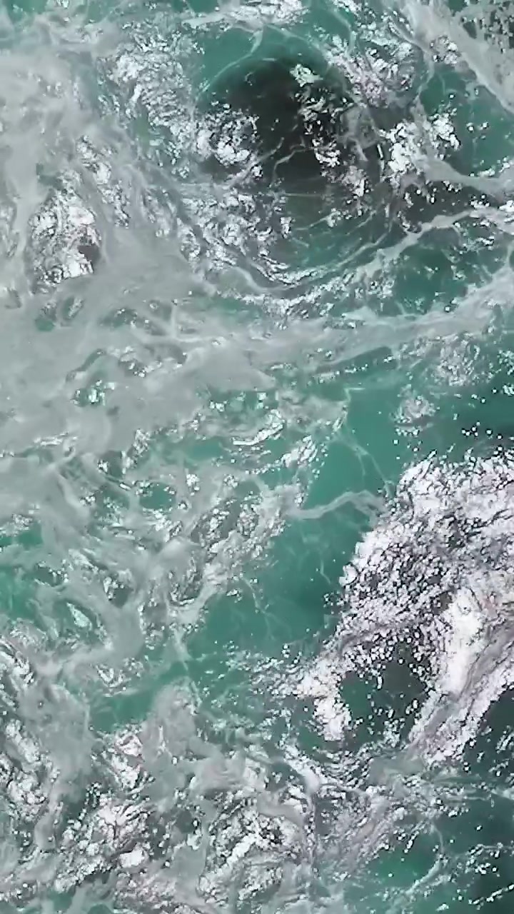 Onde d'acqua si infrangono contro le rocce in California dall'alto