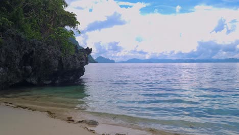 deserted tropical beach, coastal limestone rocks and calm sea, panorama