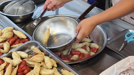 vendedor callejero de comida cocinando pasteles de pescado frito y salchichas