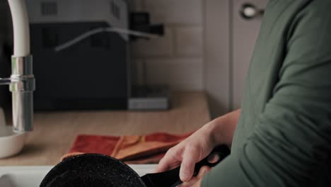 Focus-adult-caucasian-man-with-down-syndrome-washing-dishes-at-home.