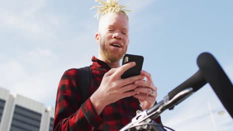 happy albino african american man with dreadlocks using smartphone