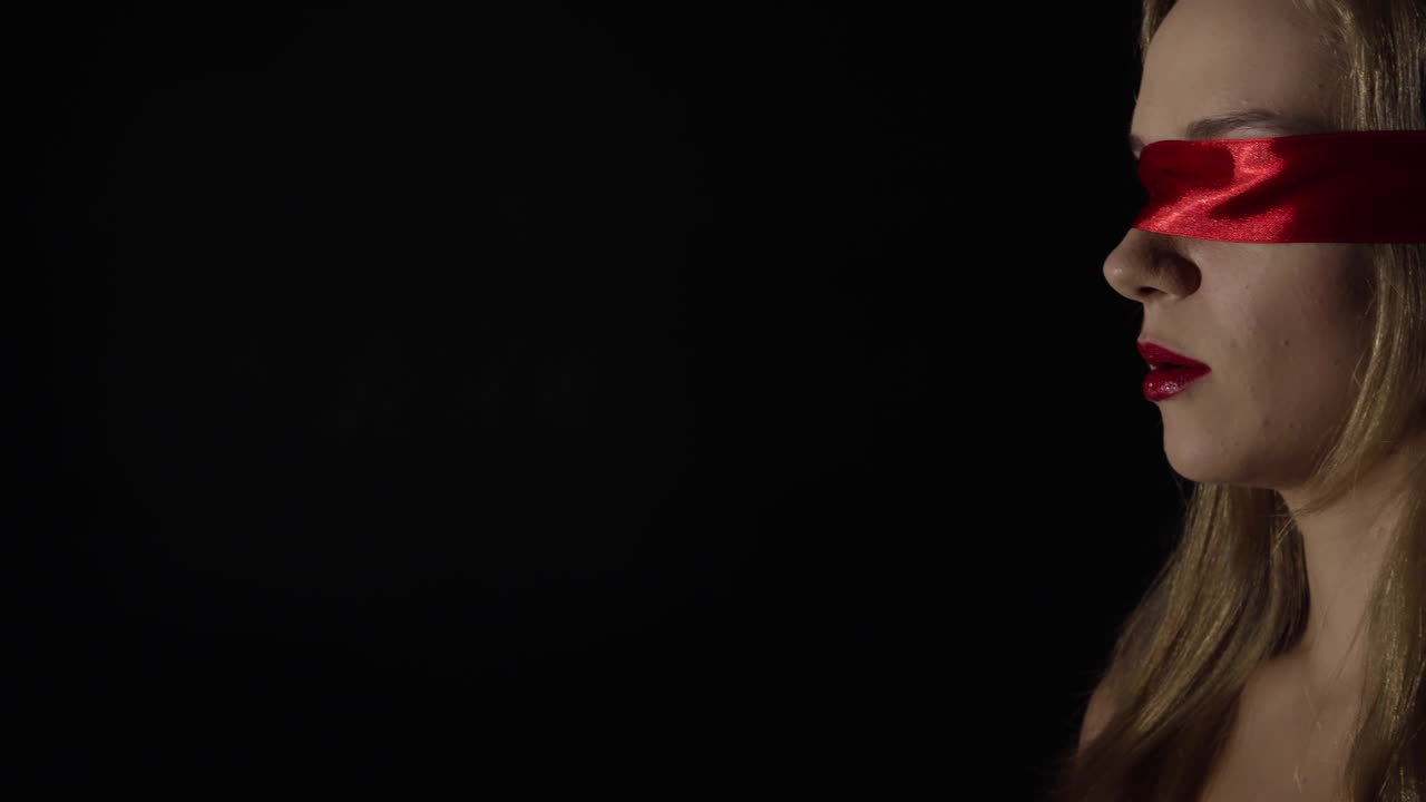 sensual retrato de la joven mujer sexy con los ojos vendados con cinta roja con la boca abierta