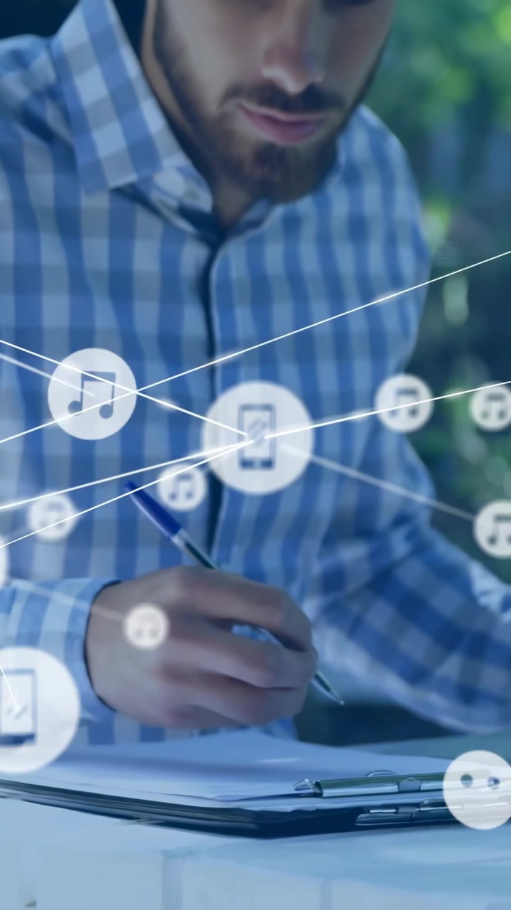 Vertikal video: Mand læner sig og skriver på en blok, telefonen gnistrer, og musiknoter vokser til et teknologisk netværkskort.