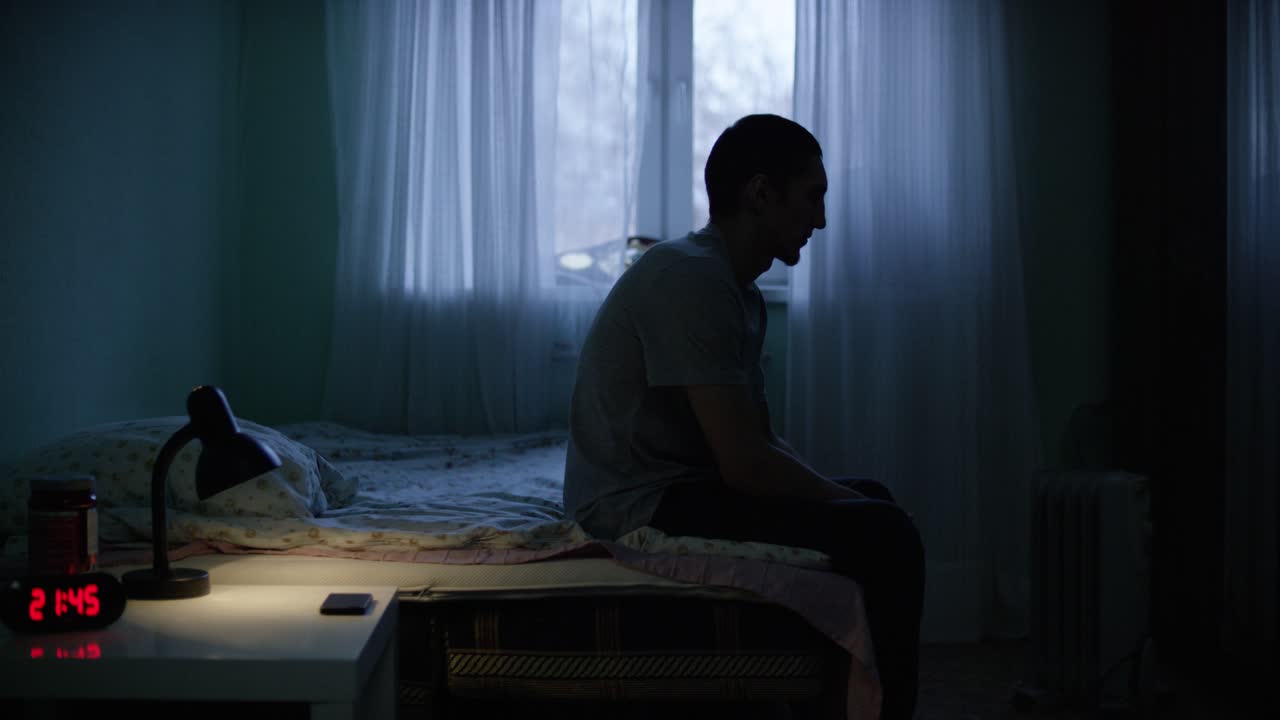 밤에 침실에서 혼자 앉아 있는 남자