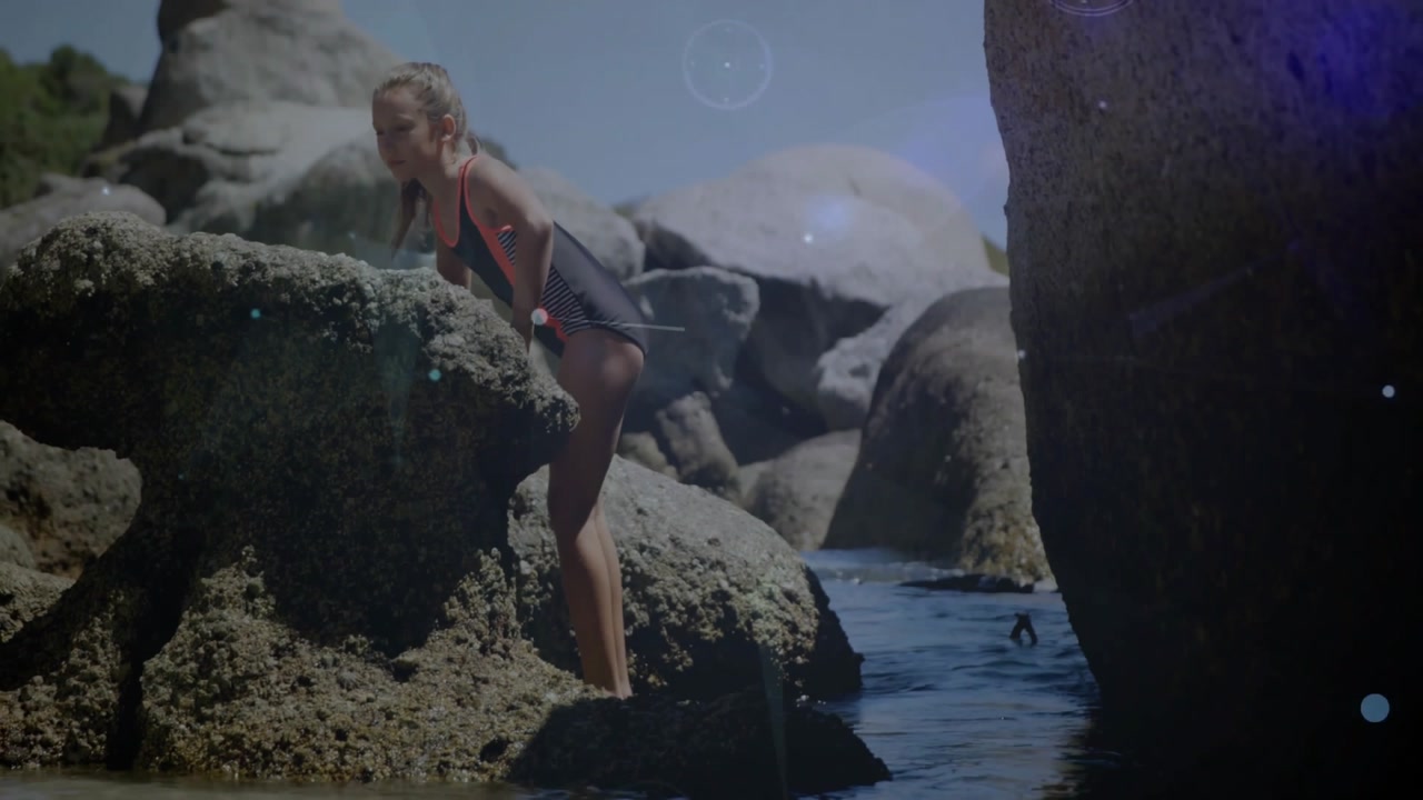 Child entering water and climbing barnacle rock, exploring tide pool with evolving tech overlays