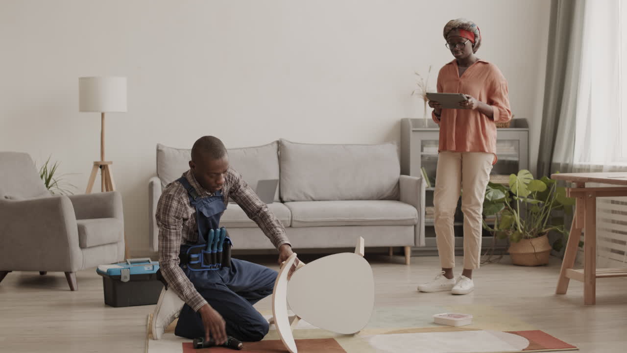 African-American Woman Watching Carpenter Assembling New Chair