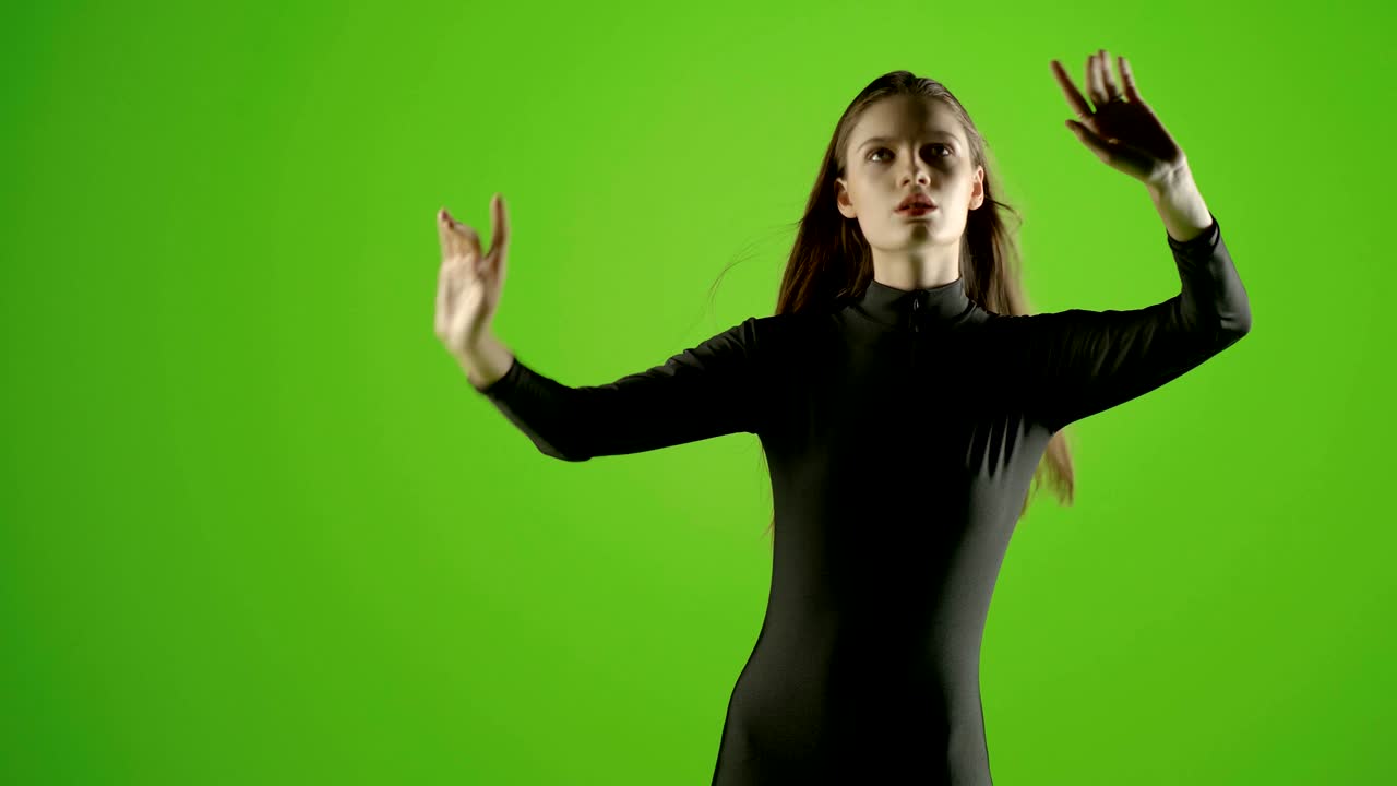 Attractive girl young fashion model virtual touch screen gesture shot in green screen studio . Interactive futuristic gesture . Medium shot . Prores shoot on Blackmagic Ursa Mini Pro