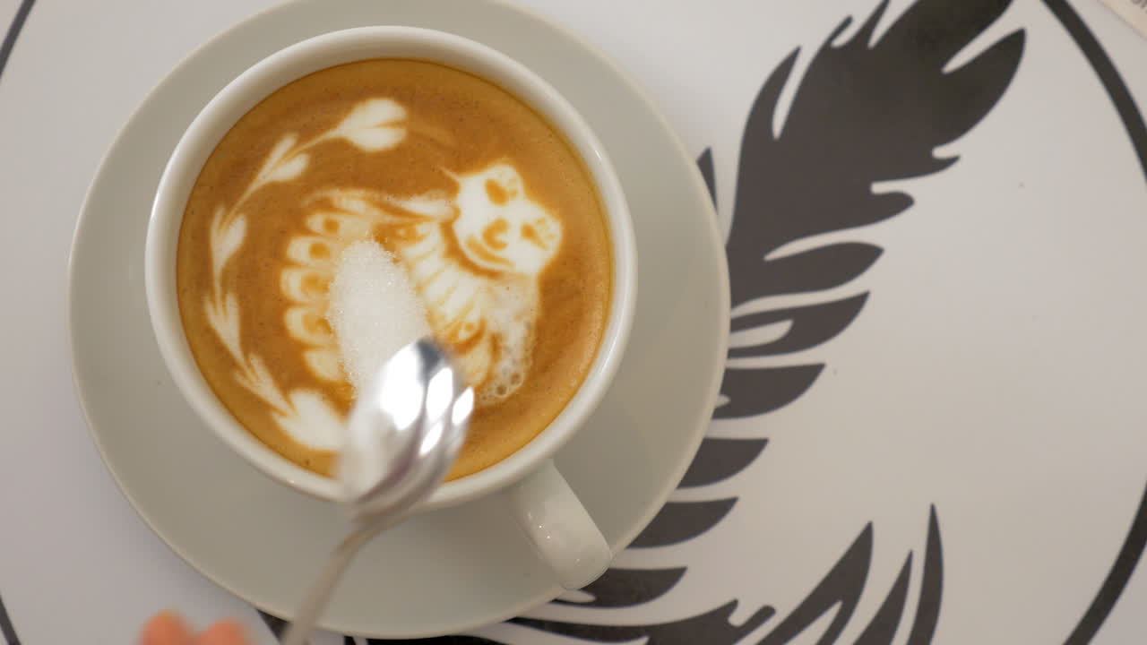 테이블은 거품과 그림으로 커피 컵으로 제공됩니다. 그리고 컵에 설탕을 넣습니다.