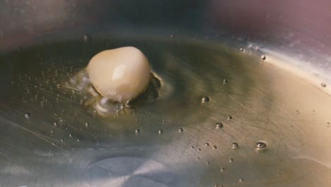 garlic clove being fried in preheated olive oil in steel pan