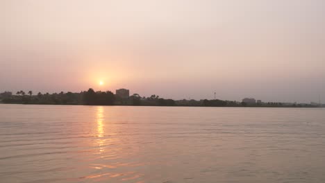 La-Puesta-De-Sol-Dorada-Se-Refleja-En-El-Río-Nilo-Cerca-De-El-Cairo,-Egipto---ángulo-Bajo