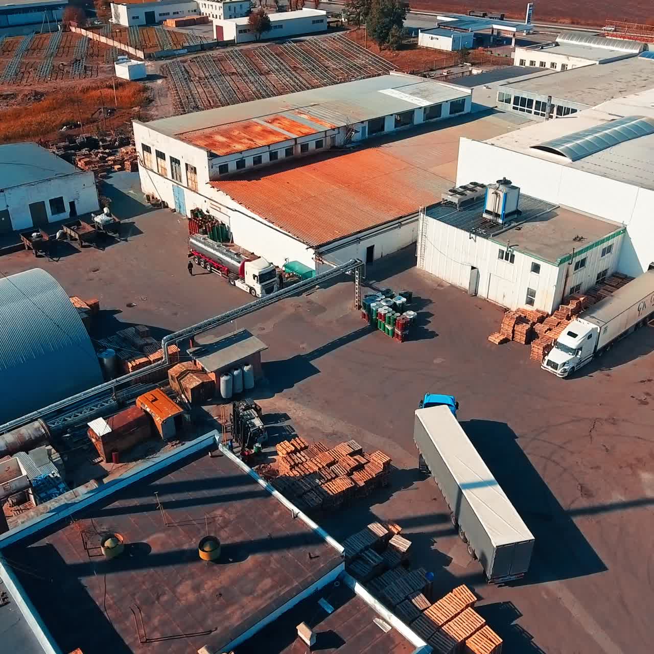 Long lorry moving by the territory of industrial warehouses. Huge truck parking closer to a ramp for loading