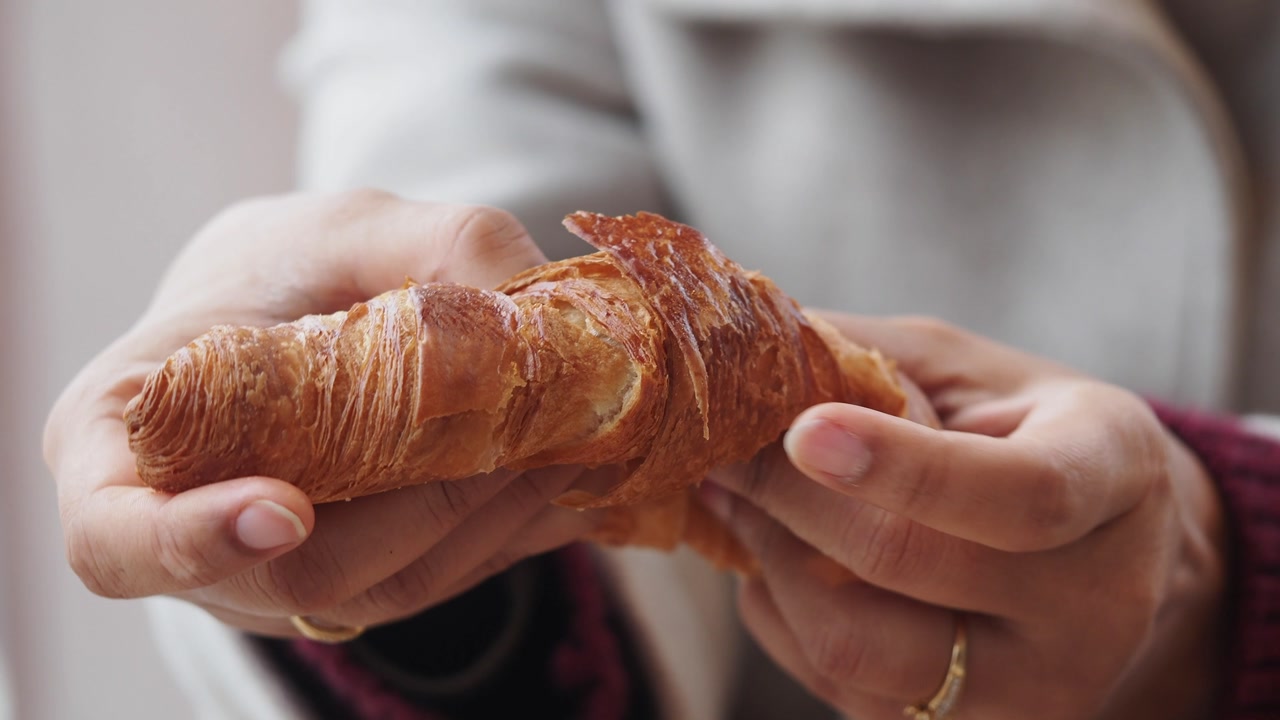 Close-Up of Hands Tearing a Fresh Croissant
