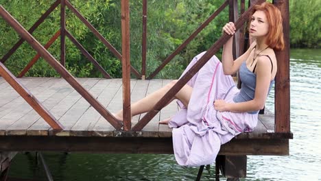 mujer sentada en un muelle de madera junto a un lago