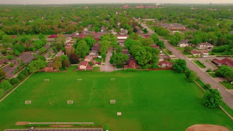 Vista-Aérea-Aérea-De-Casas-En-Los-Suburbios-De-Chicago-Adyacentes-A-Múltiples-Campos-De-Fútbol.