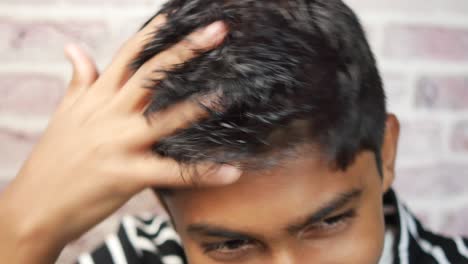 Teenage-boy-scratching-head-against-black-background