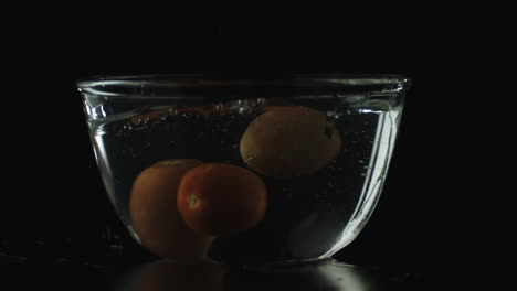 slow-mo of tomatoes dropping in bowl of water