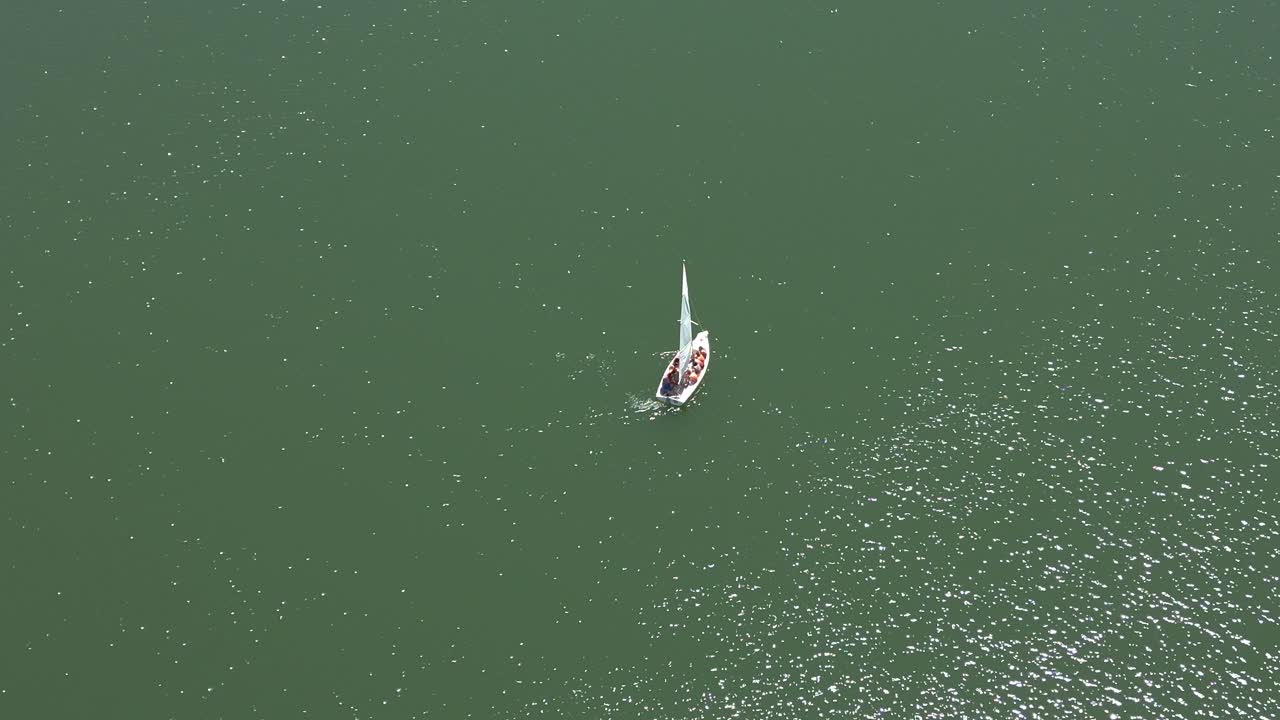 Sailboat sailing on green water on sunny day. Aerial view. Andalusia. Spain.