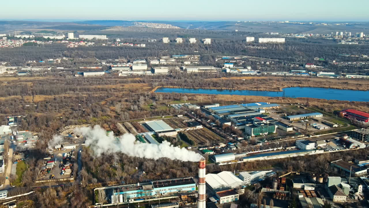 Aerial drone view of Chisinau. Thermal station with smoke coming out of the tube. Buildings, roads and bare trees. View over the hills. Good weather. Moldova