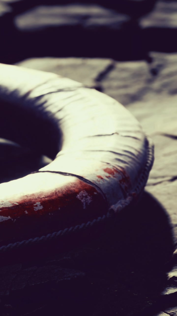 Lifebuoy resting on a sandy surface in bright sunlight near water