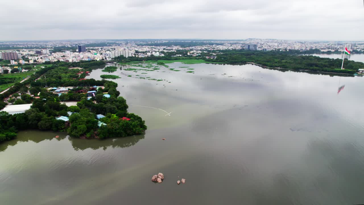 Lago Hussain Sagar con cielo, treno in movimento e città verde a Hyderabad. Diurno, semi-orbita, ripresa con drone, 4K