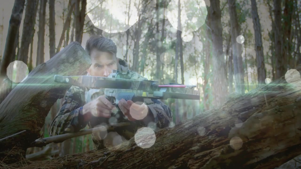 Hunter Aiming Crossbow While Crouched Behind Fallen Log in Forest