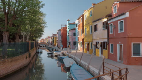 waterside street with brightly painted houses and walking people burano italy