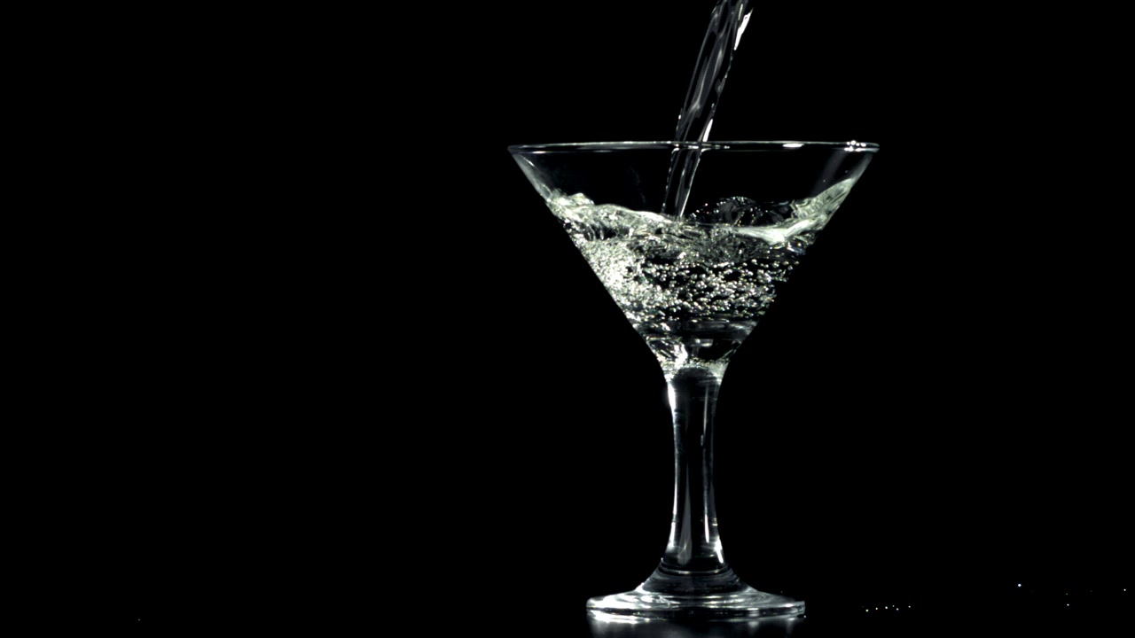 Liquido trasparente versato in un bicchiere da Martini al rallentatore