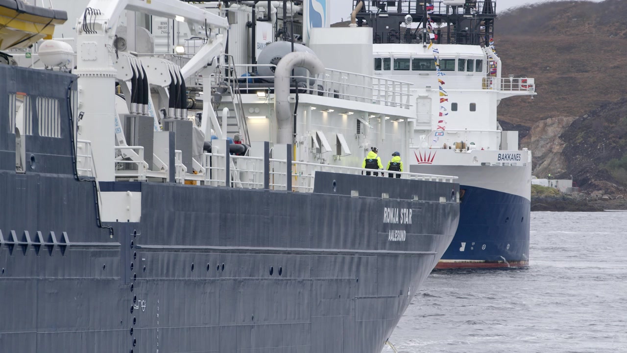 Slow motion shot of two crew members walking on the deck of a large fishing ship. Shot near Stornoway on the Isle of Lewis, part of the Outer Hebrides of Scotland.